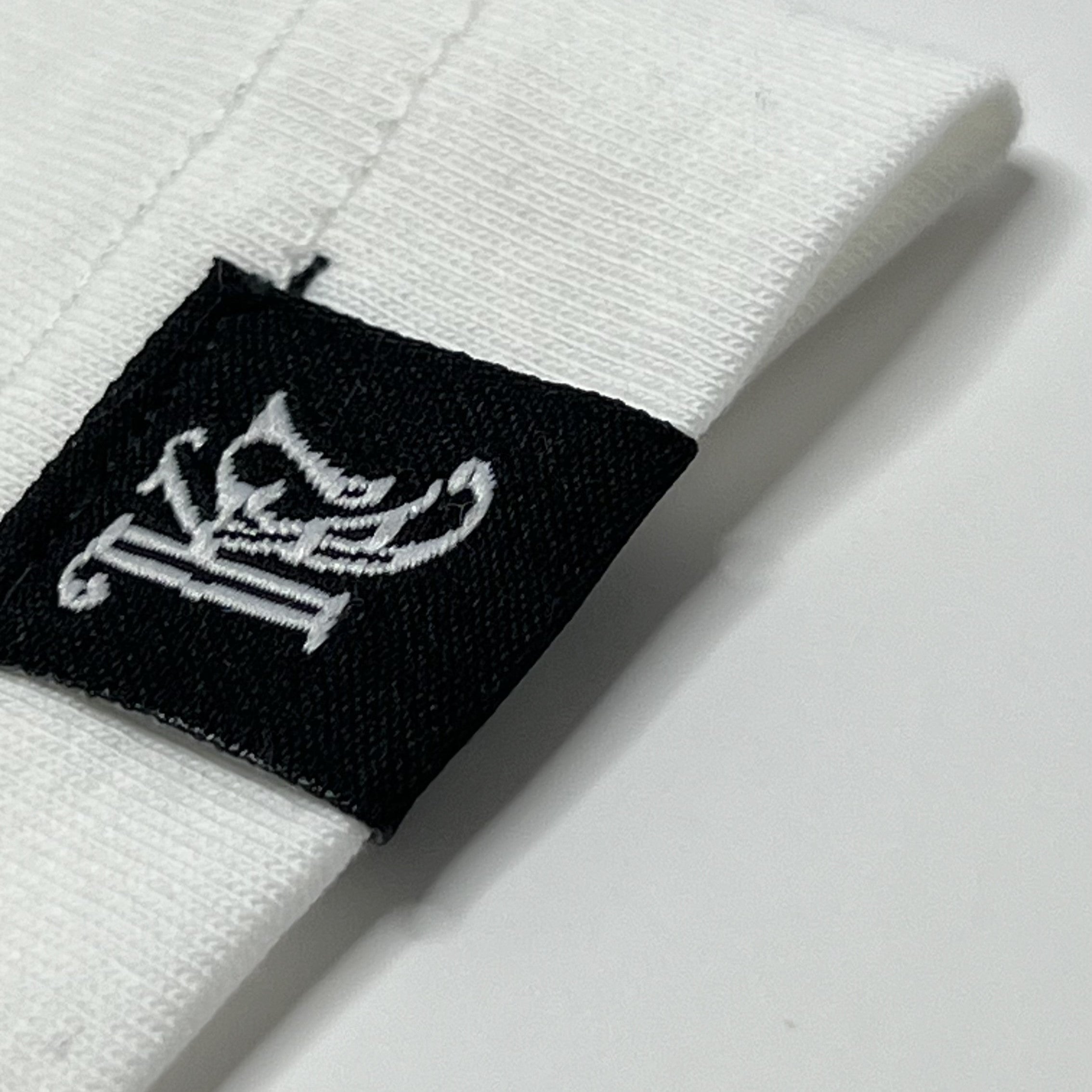 Woven KC monogram label on sleeve of white King Cyrus t-shirt